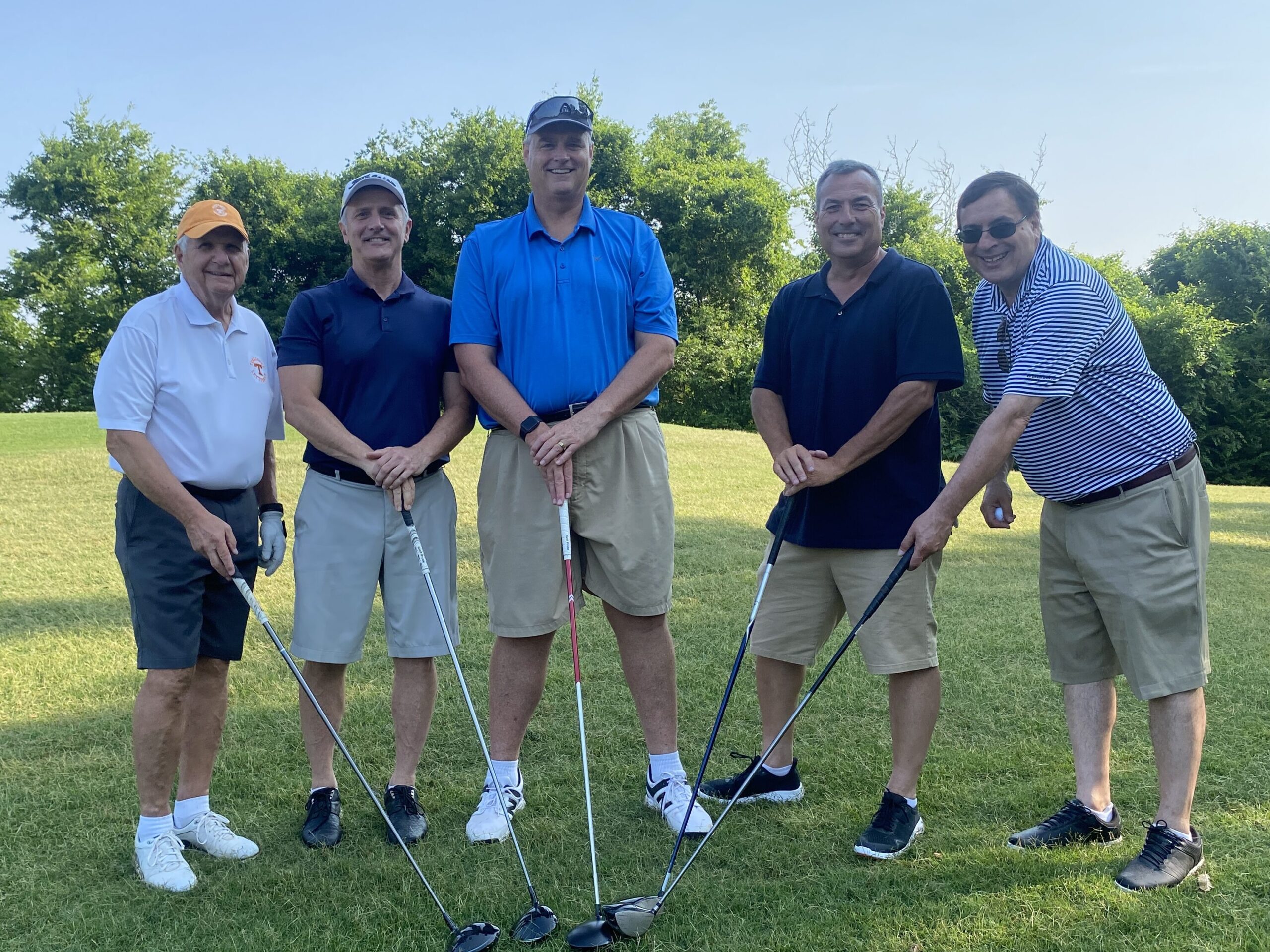 five golfers put clubs together and smile for picture