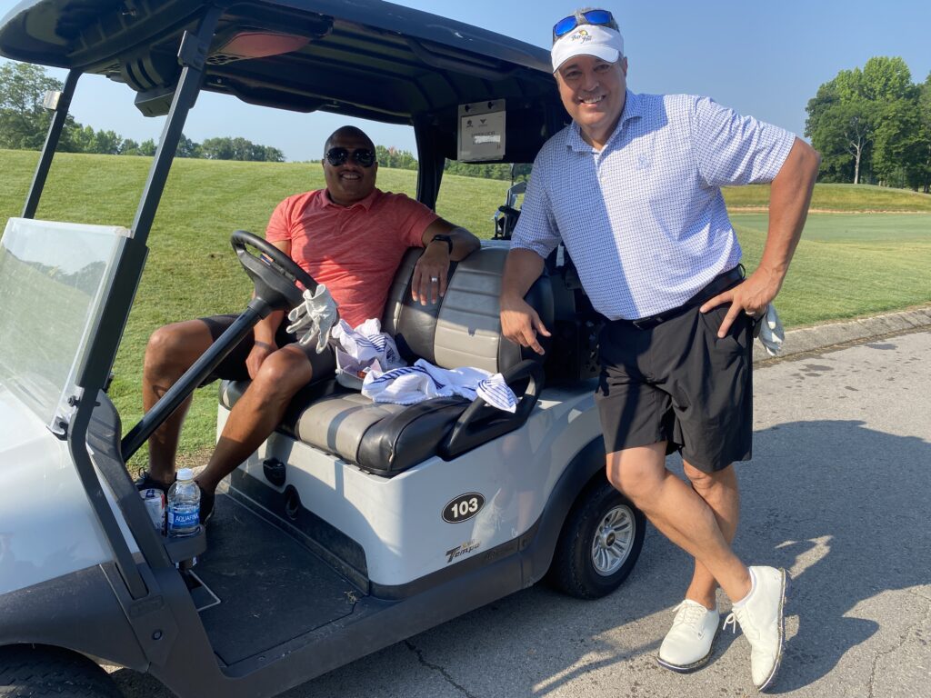 man leans against golf cart